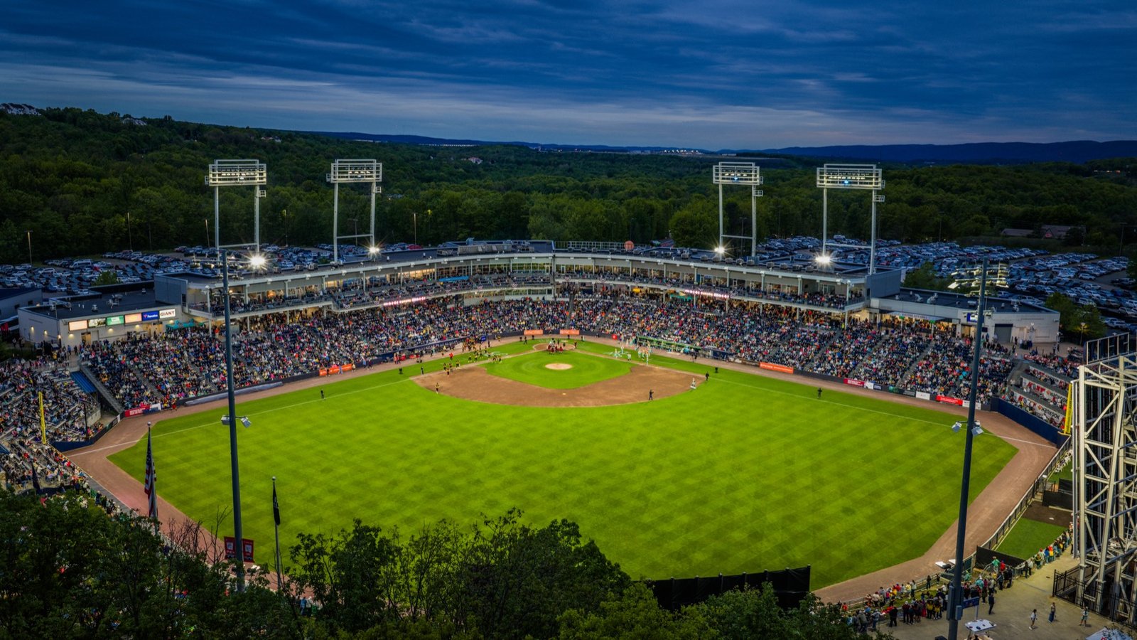 Packed minor league ballpark under the lights at dusk