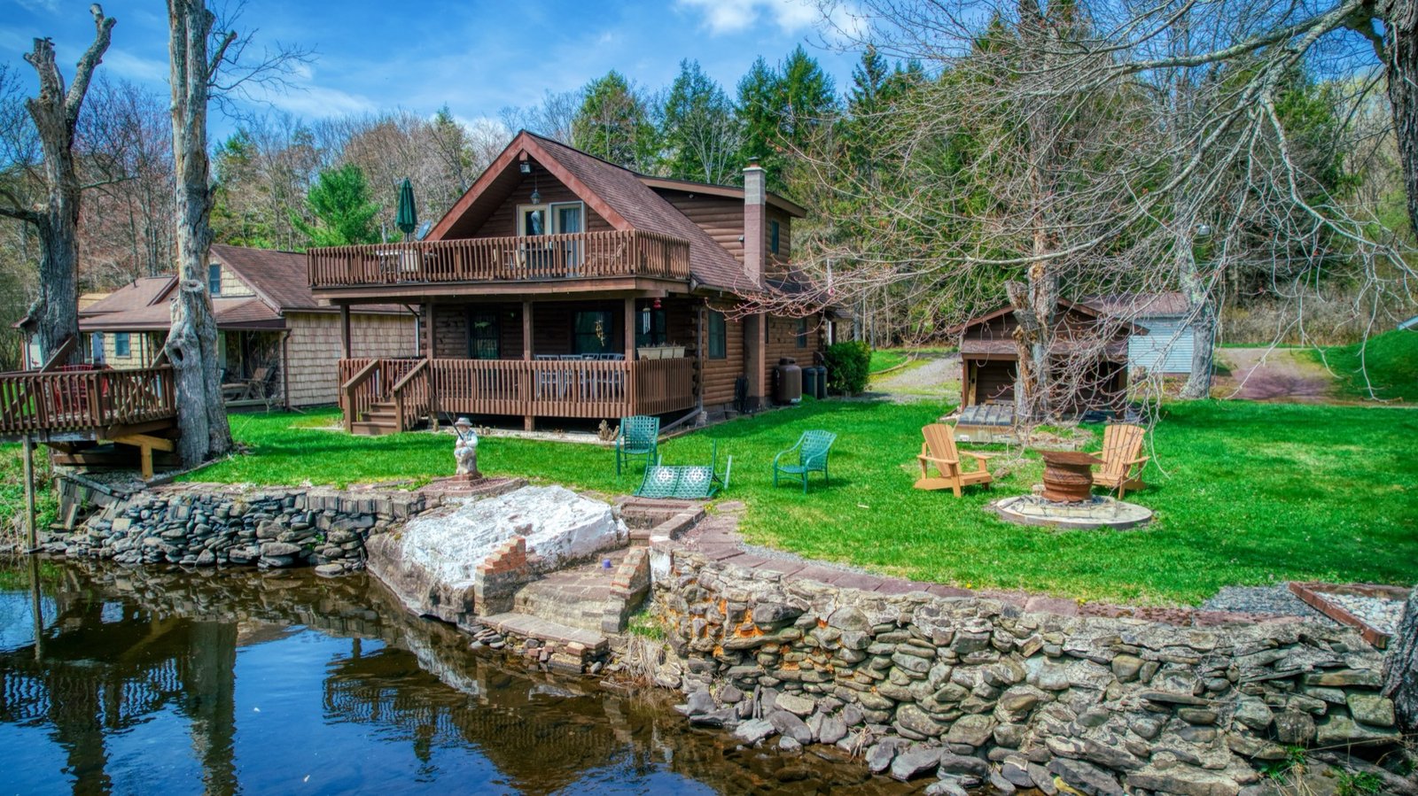 Log home with a wraparound deck on the edge of a pond
